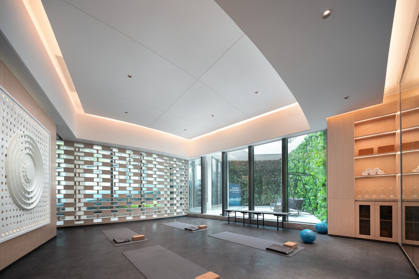 Yogastudio med mattor och block vända mot fönster med en vertikal trädgård.