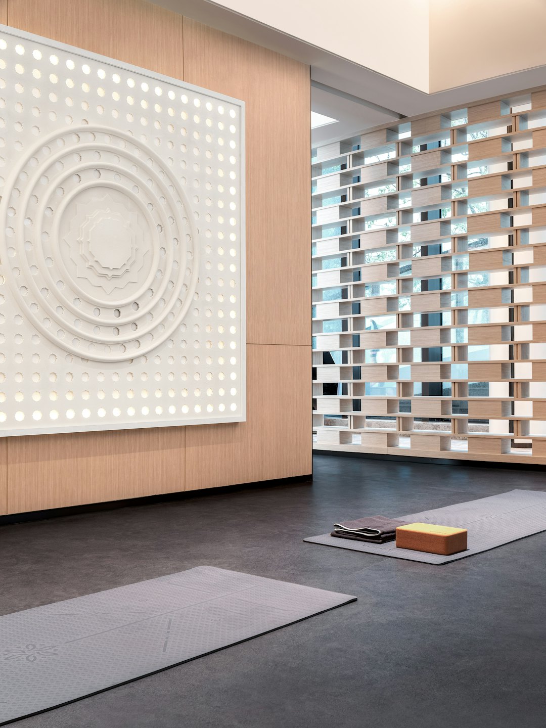 Två grå yogamattor ligger på studions golv.